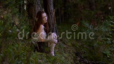浪漫的年轻女人独自坐在树林里，触摸她的腿和手掌，因为她<strong>有点</strong>冷。